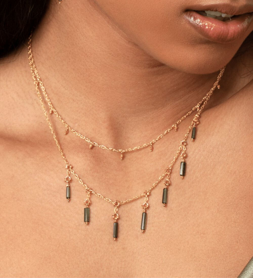 A woman wearing layering necklaces from Kate Winternitz Jewelry embellished with beading, textural chain, and woven elements.