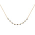 A delicate gold chain necklace featuring a curved line of small, faceted black beads separated by tiny gold links, displayed against a solid white background.