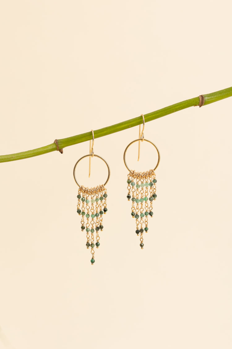 Emerald fringe earrings hanging on a branch