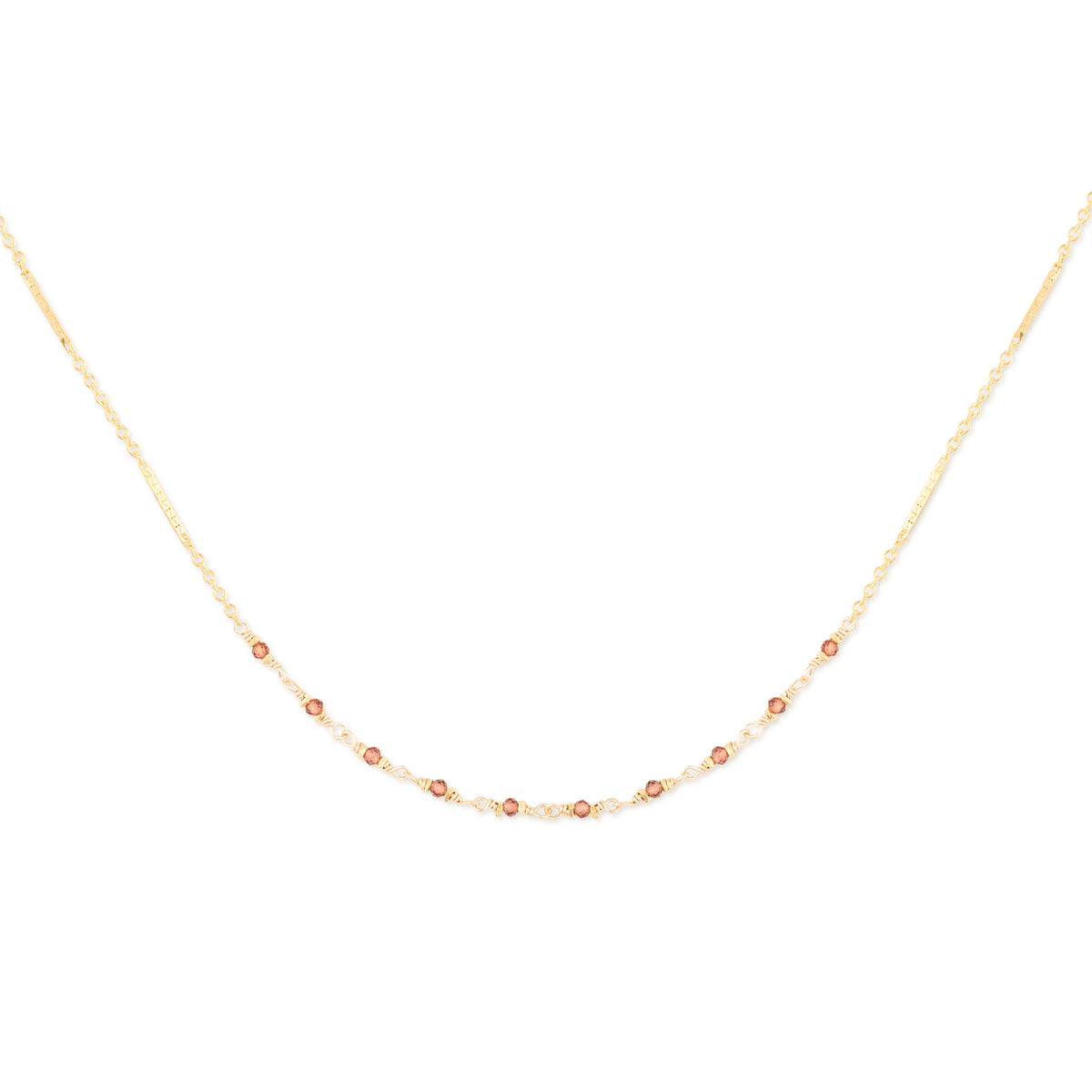 Delicate gold necklace with small garnet beads on a white background