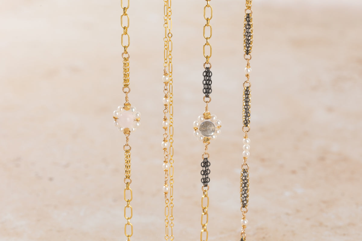 Four gold bracelets with different designs on a beige background