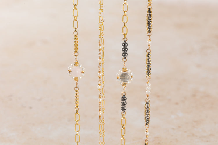 Four gold bracelets with different designs on a beige background