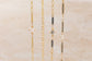 Four gold bracelets with different designs on a beige background
