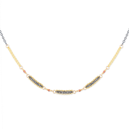Mixed metal necklace with natural faceted garnets on a white background