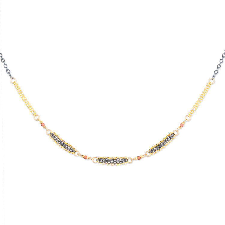 Mixed metal necklace with natural faceted garnets on a white background