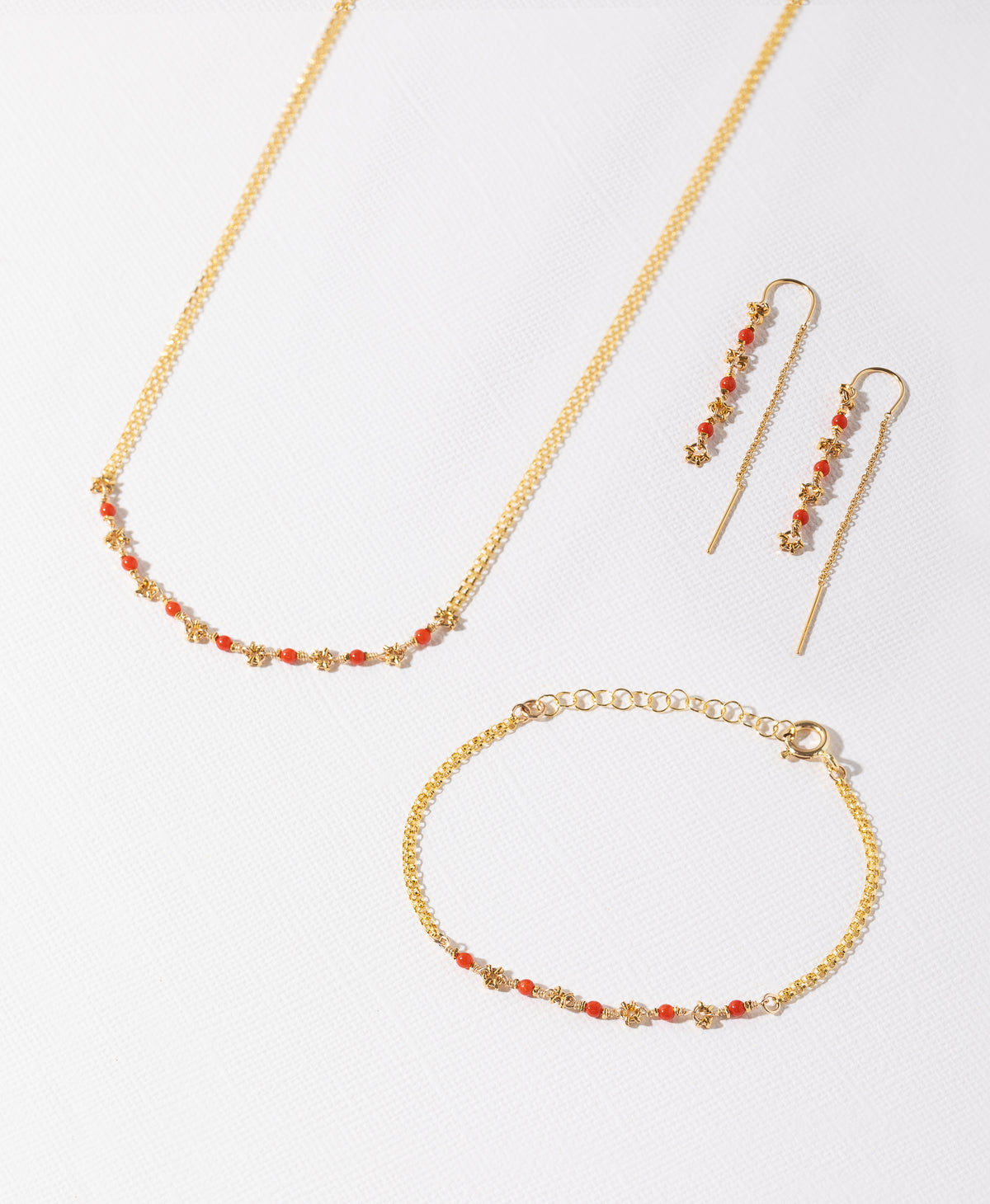 Coral and gold necklace, threaders and bracelet on a white background 