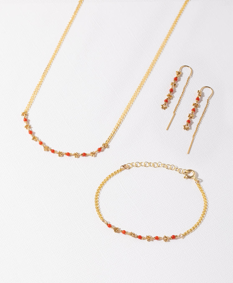 Coral and gold necklace, threaders and bracelet on a white background 