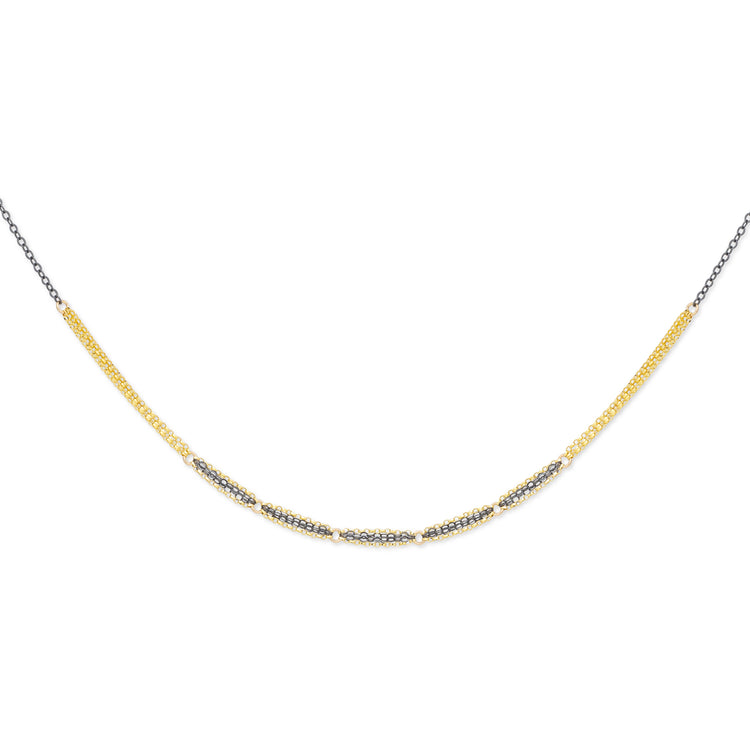 A double-stranded mixed metal necklace with a combination of gold-fill and oxidized sterling silver showcasing a patterned chain design.