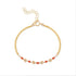 A gold-colored bracelet featuring small red coral beads and gold accents, with a chain clasp.