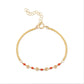 A gold-colored bracelet featuring small red coral beads and gold accents, with a chain clasp.
