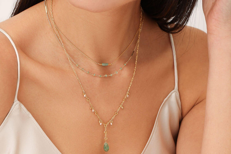 A modern birde wearing layering jewelry from Kate Winternitz Jewelry featuring green tourmaline semi precious stones.