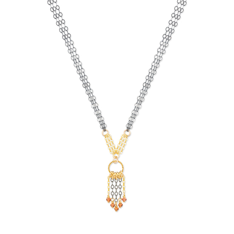 Necklace with a gold and oxidized silver pendant with garnet stones on a white background