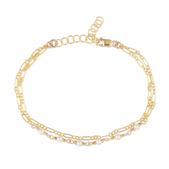 Gold chain bracelet with pearl accents on a white background