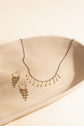 Miori necklace and Akina emerald earrings displayed in a beige tray 