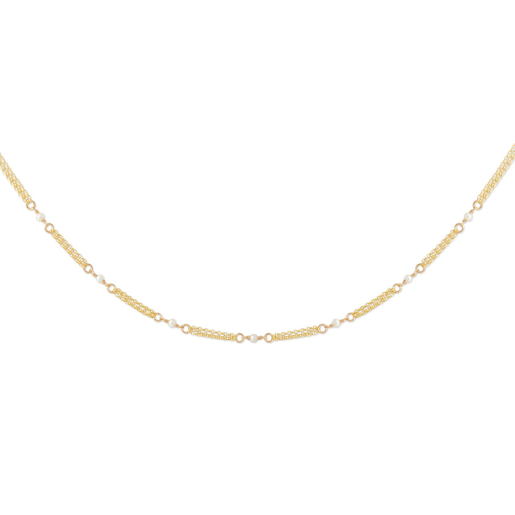 A delicate gold chain necklace with alternating textured oval links and small round clear stones, displayed in a curved shape against a plain white background.