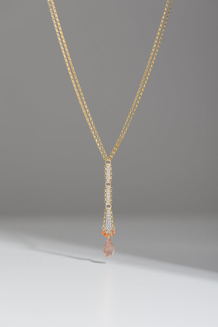 Mixed metal Y necklace with sunstone drop and accent beads hanging on a gray backgroud