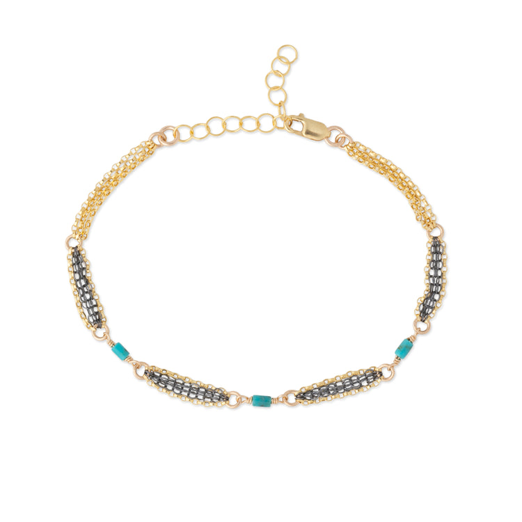 A gold chain bracelet featuring three horizontal rows of oxidized silver chain, accented with turquoise blue beads, displayed on a clean white background.