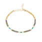 A gold chain bracelet featuring three horizontal rows of oxidized silver chain, accented with turquoise blue beads, displayed on a clean white background.