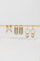 Three pairs of gold bar earrings featuring emerald gemstones and dangling fringe chains, displayed together on a white background.