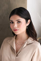 A model in a tan shirt against a beige backdrop, wearing the layered Astrid and Alexis necklaces paired with the Gemma earrings.