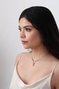 A model looking out a window while wearing Aurora, a draped gold and oxidized sterling silver necklace featuring a flashing opal.